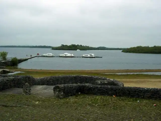 Three white cruisers moored along a long jetty off the shore at Knockninny, with wooded islands across the grey water of Upper Lough Erne.