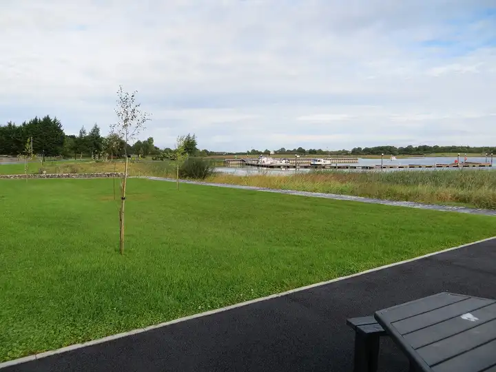 The floating jetty and moored boats at Portrunny seen across the lawn of the lakeside picnic area, with a picnic table in the foreground.