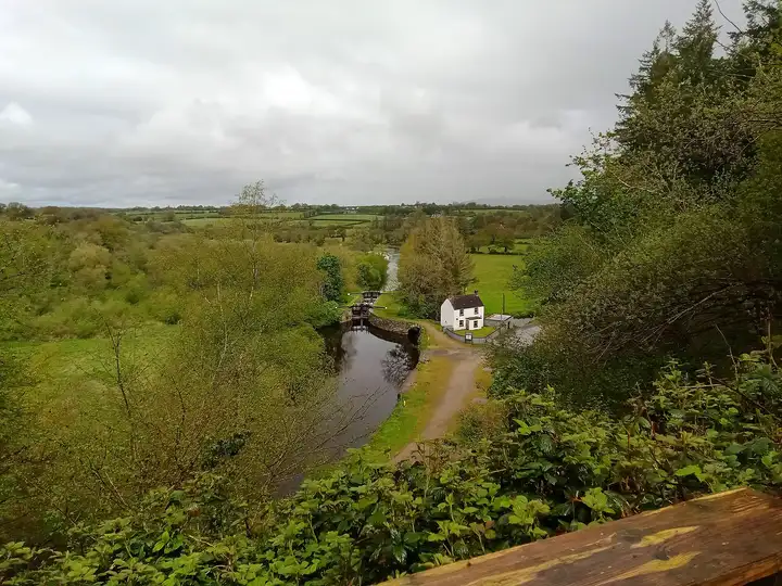 Clashganny Lock and its white lock keeper’s house seen from the wooded hillside above the river valley.