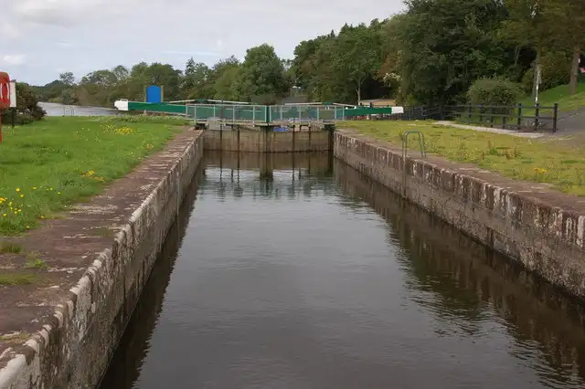Die gemauerte Kammer der Schleuse Carnroe mit Blick auf die hinteren Tore und ihre grünen Geländer, beiderseits grasbewachsene Ufer.
