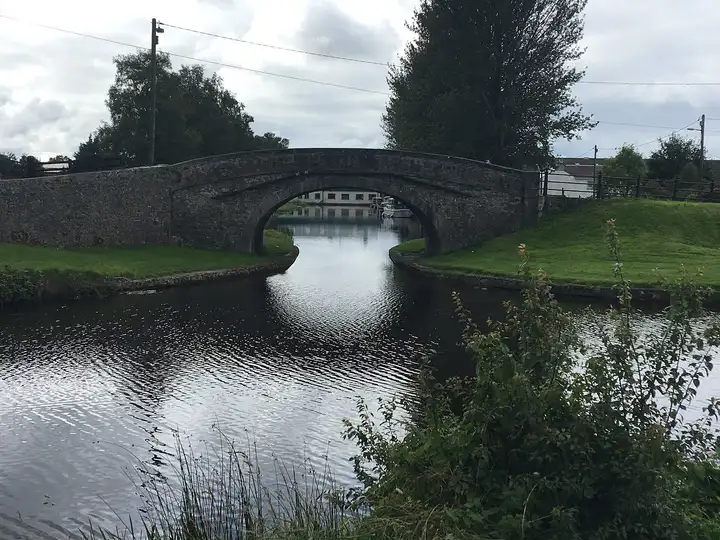 Die Bury Bridge in Tullamore über den Kanal hinweg gesehen, ihr Steinbogen gibt den Blick auf das Wasser und die Gebäude dahinter frei.
