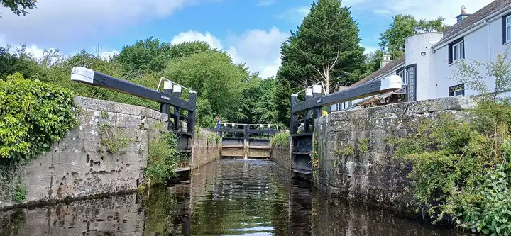 Ardreigh Lock seen from the water, with its stone walls, black balance beams and the white lock house on the right.