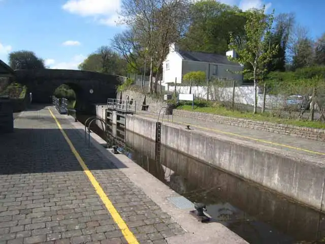 Drumshanbo Lock on a sunny day, with a cobbled lockside marked by a yellow line and a stone bridge at the far end of the chamber.