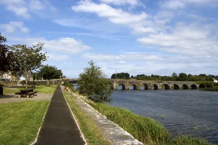 A riverside path runs past picnic tables and the village houses towards the stone bridge across the Shannon at O’Briensbridge.