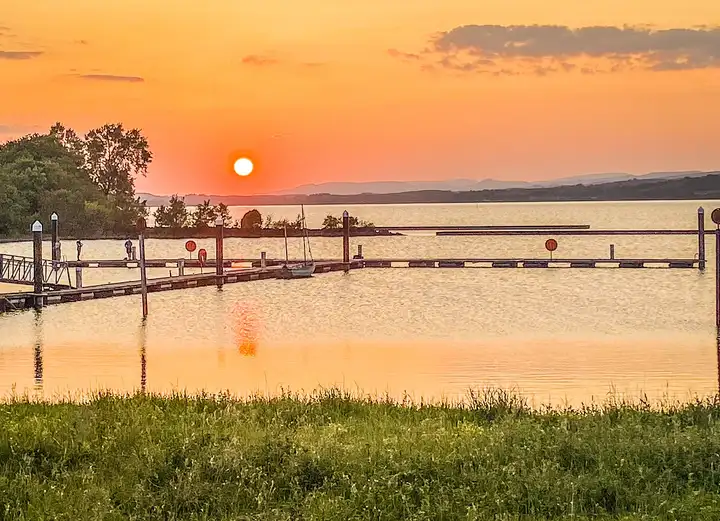 The sun sets over Lough Allen behind the floating jetties of Cleighranmore marina, turning the calm water orange.