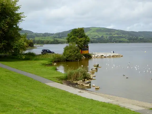 The small stone jetty at Ballycuggaran beach, with gulls on the water and green hills across the lake.