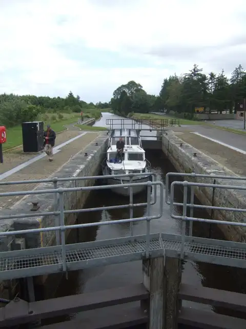 A cruiser in the chamber of Kilclare Upper Lock (Lock 9), seen over the railings of the lock gates, with the lockside path and the canal stretching away beyond.