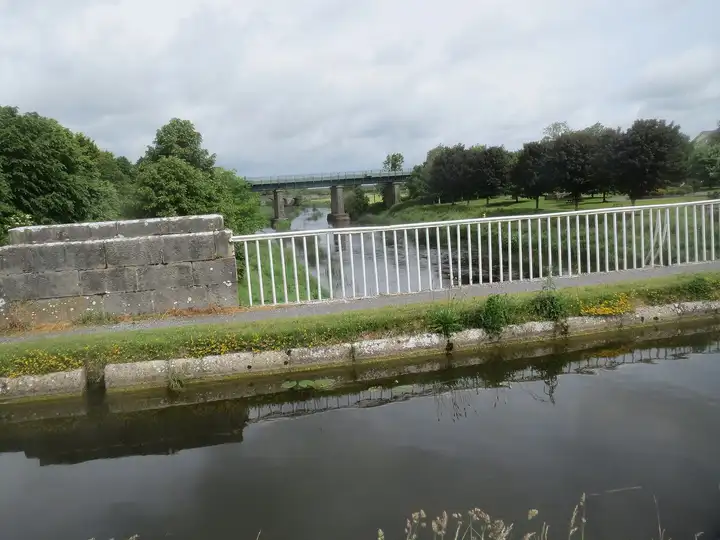 The River Barrow seen from the aqueduct at Monasterevin, flowing away beneath a railway viaduct beyond the canal railings.