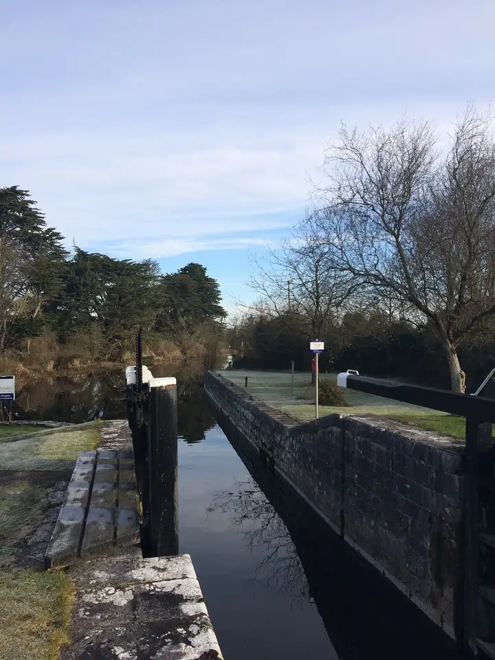 Le sas de pierre de l’écluse 46 à Clondra, par lequel les bateaux quittent Richmond Harbour, s’étend sous un pâle ciel d’hiver, avec du givre sur l’herbe et des arbres dénudés au-delà.
