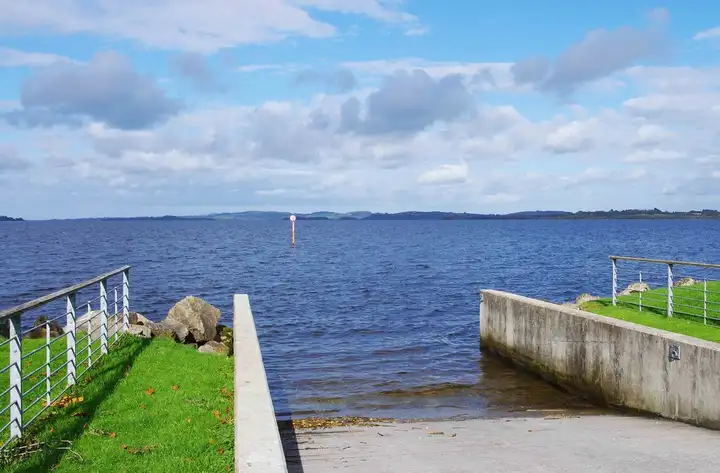 The concrete slipway at Garrykennedy running down into Lough Derg, with a navigation marker out on the lake.