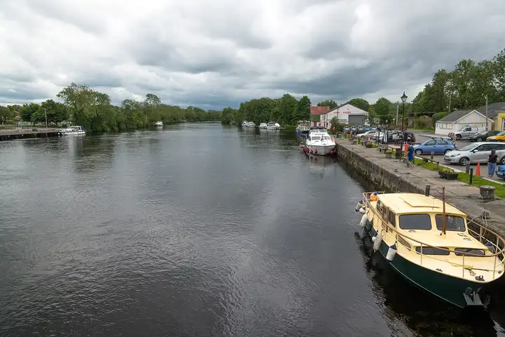 Seen from the bridge, the Shannon stretches away past Roosky’s busy village quay, where a cream-and-green cruiser and other boats lie along the stone edge.