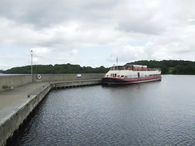 The red and white hotel barge Shannon Princess moored at the outer wall of Terryglass harbour on a cloudy day.