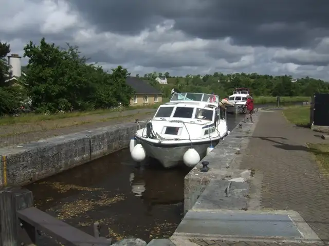 A white cruiser in the chamber of Lisconor Lock (Lock 12) at Kilclare, with a second boat close behind and dark clouds overhead.