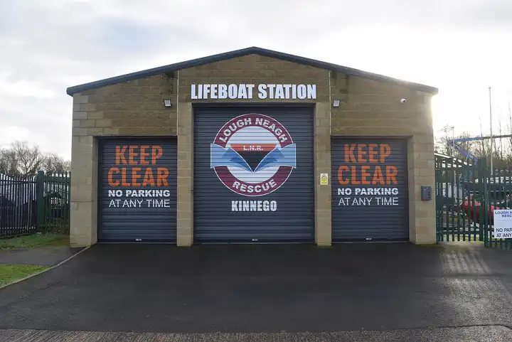 Die Rettungsstation von Lough Neagh Rescue in der Kinnego Marina, ein Gebäude aus Steinblöcken mit drei Rolltoren und dem runden Logo des Rettungsdienstes.