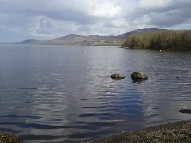 Calm water and boulders off the shore at Ballycuggaran, looking across Lough Derg to the hills on the Tipperary side.