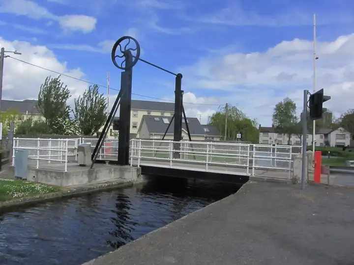 The lifting bridge over the Barrow Line at Monasterevin, with its overhead wheel and black frame above the canal, seen from the quay at water level.