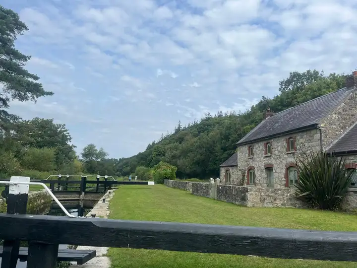 St Mullins Lock, the last on the Barrow, with its balance beams, a wide lawn and the stone lock keeper’s house below wooded hills.