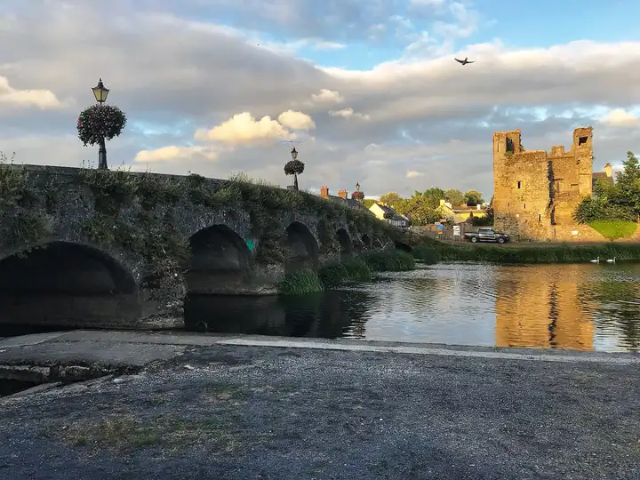 Abendsonne auf dem Black Castle neben der vielbogigen Brücke von Leighlinbridge, von der Slipanlage aus gesehen, mit Schwänen auf dem Fluss.