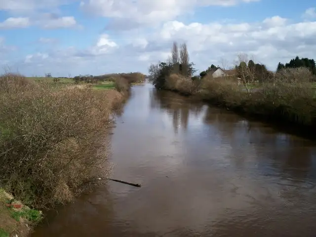 The brown water of the Maghery Canal runs straight between scrubby banks towards Lough Neagh, seen from the road bridge.