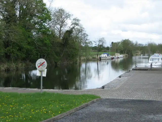 The paved quay of Lecarrow Harbour beside the tree-lined canal, with motor cruisers moored along the bank.
