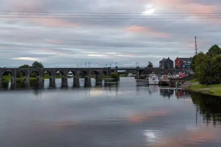 Evening view along the Shannon to the long stone bridge at Shannonbridge, with cruisers moored at the village quay and Luker’s pub on the right.